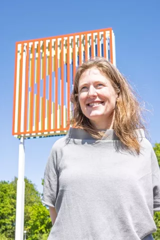 De kunstenaar poseert voor haar beeld.